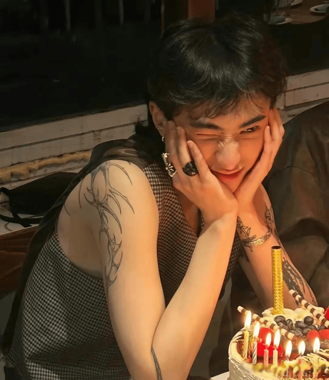 恩利在照片中穿着马甲,露出了手臂上的纹身,双手托腮,挤着眼睛做出