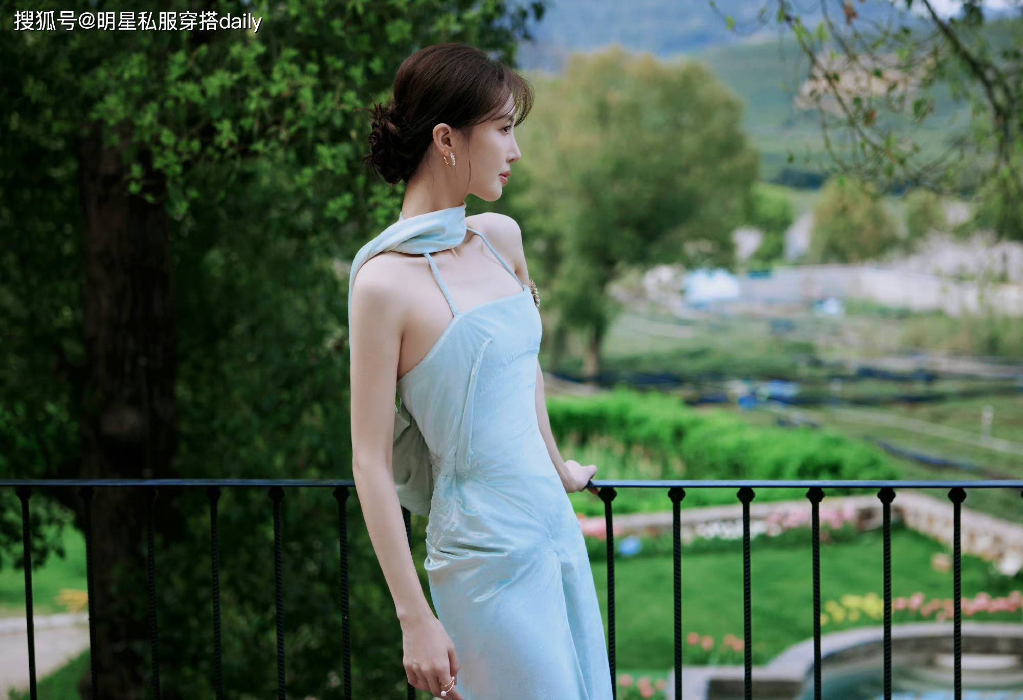 吉娜穿着一件冰蓝色的挂脖连衣裙，与美丽的风景融为一体，是大自然喜爱的美丽。
