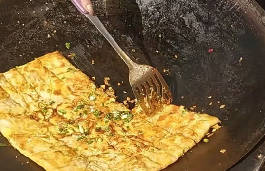 武汉最有名三鲜豆皮小吃用糯米和面糊摊在锅里顾客排队买