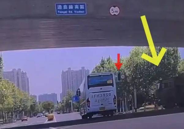 白色车身的大巴车在盘香路上呈直线行驶,即将驶过高架桥下时,横向的
