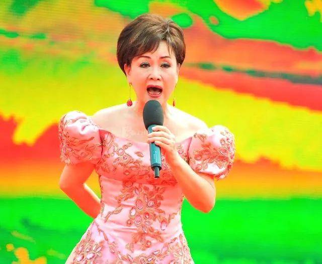 在这张温馨的照片中,站在中间的是李谷一,她身着一袭粉红色长裙,优雅