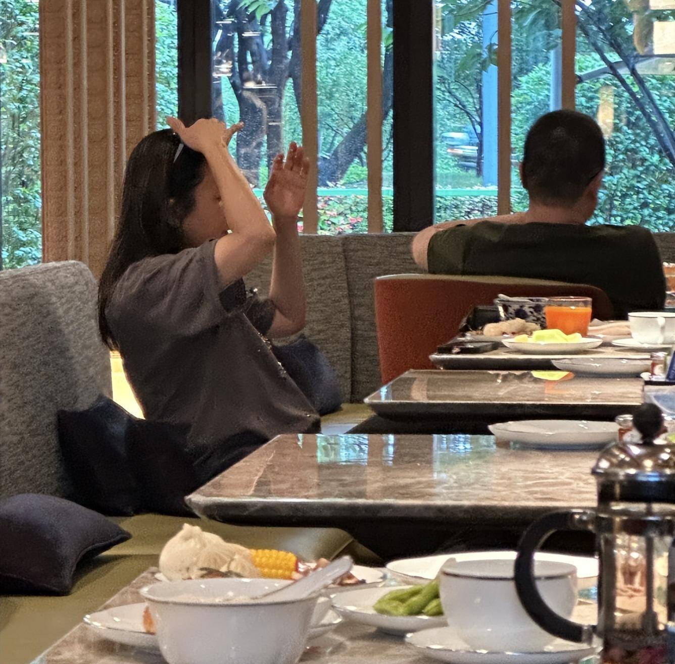 侧脸,穿着打扮更是相当朴素,一件灰色短袖t恤,为了方便吃饭还戴了一个