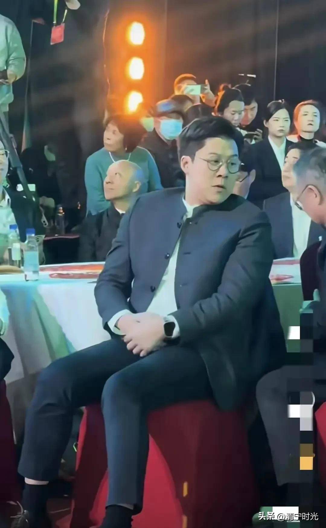 霍启刚又胖了参加百花迎春晚会裤子短半截手上拿着两部手机