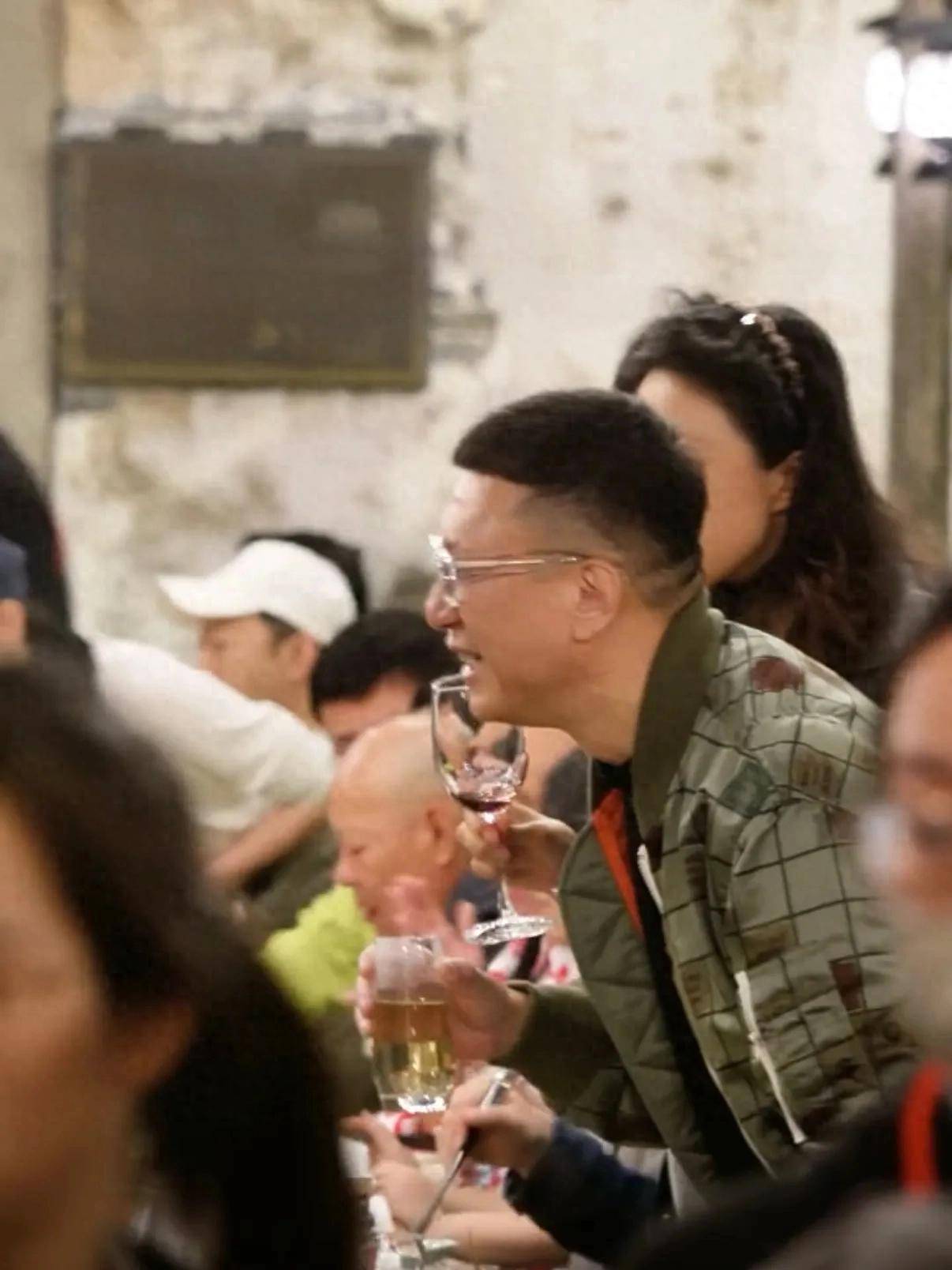 孙红雷手持茶杯微微前倾礼貌聆听;王骏迪举着红酒杯神态温柔间或