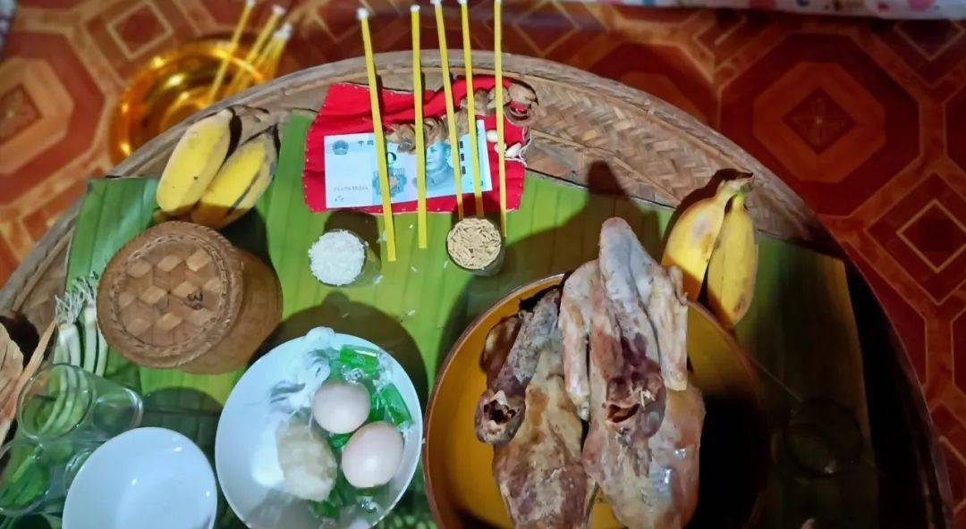 客厅中央摆放有1个圆形篾桌,蔑桌上摆有1块红布,1条用白线串起来的