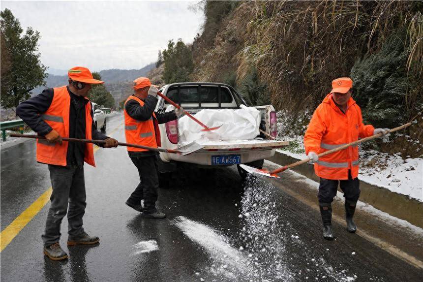 竹山县公路养护中心工作人员在242国道上庸路段抛撒融雪剂.