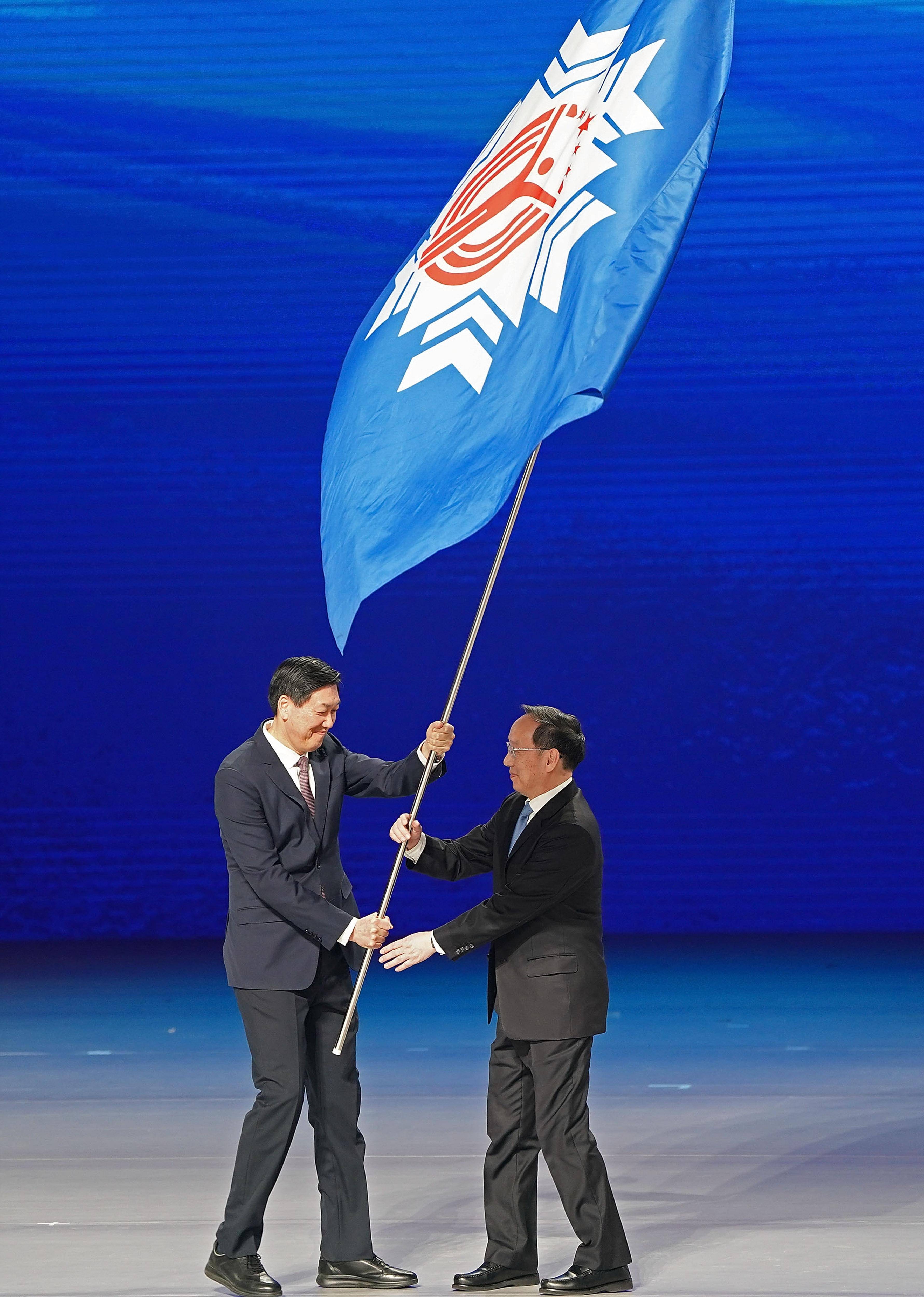 与第十五届全国冬季运动会承办地辽宁省省长李乐成在闭幕式上交接会旗