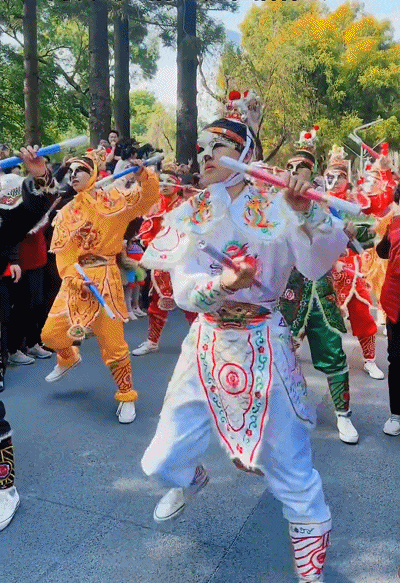 表演的队员们脸上并无化上脸谱,而是戴着面具,手持两根棍子随着节拍