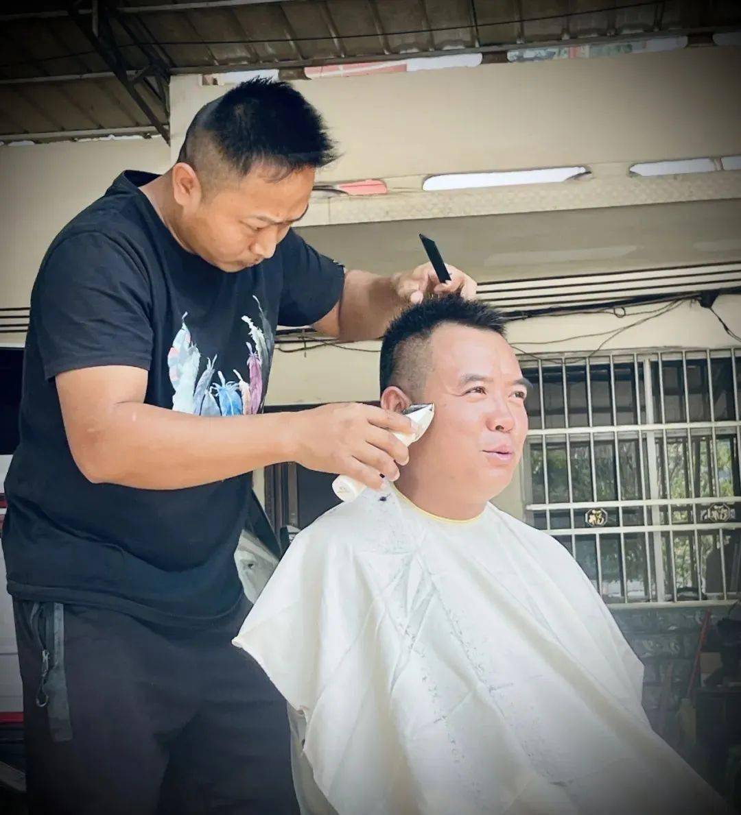 一把剪刀一把推子在他手中翻飞一张围毯装下了头发也承载着他对