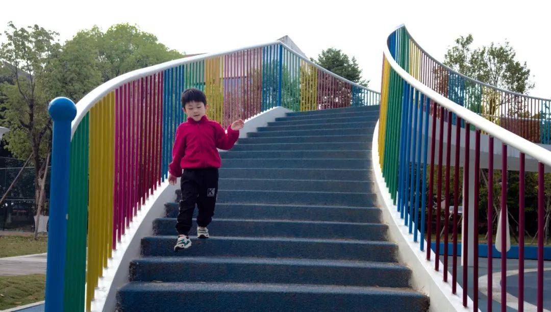孩子们爬上小楼梯来到平台上,坐在滑滑梯的起点端用力在滑滑梯的扶栏