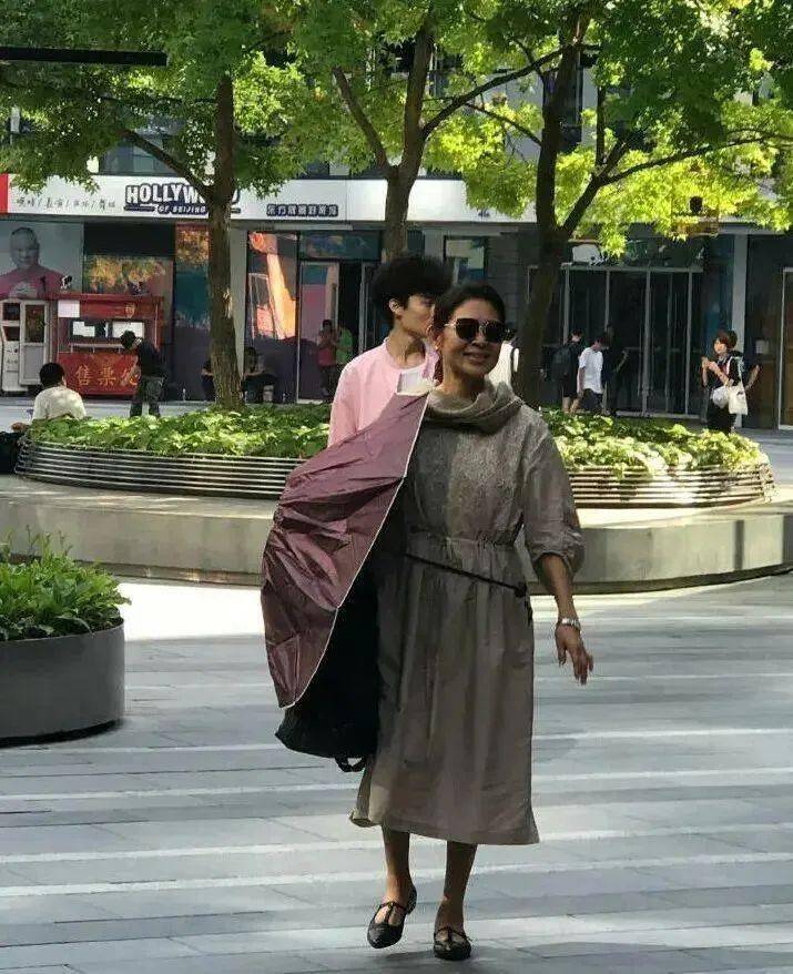 左手的深紫色雨伞和右手的手提包,不仅实用,更为整体穿搭增添了一抹