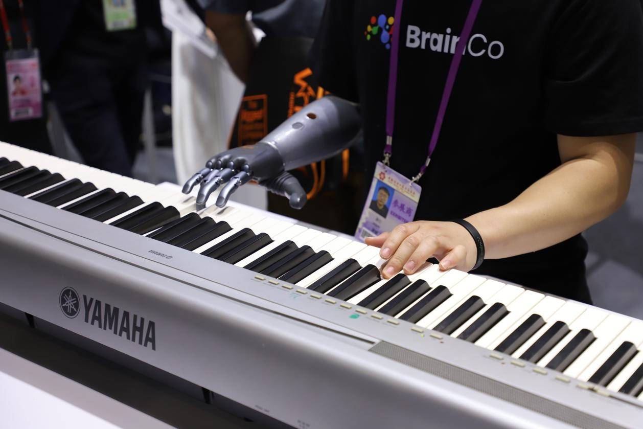 人民网 周睿摄在浙江强脑科技有限公司展台前,演奏者用智能仿生手替代