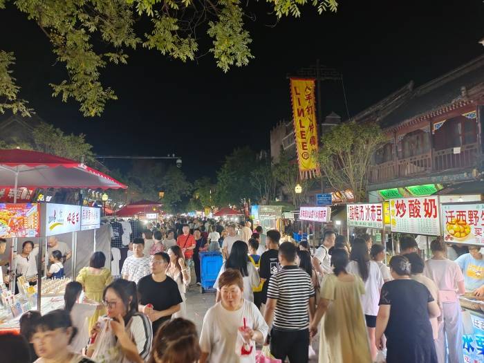 游客来到鼓楼夜市,书店街夜市品尝小吃,购买旅游纪念品