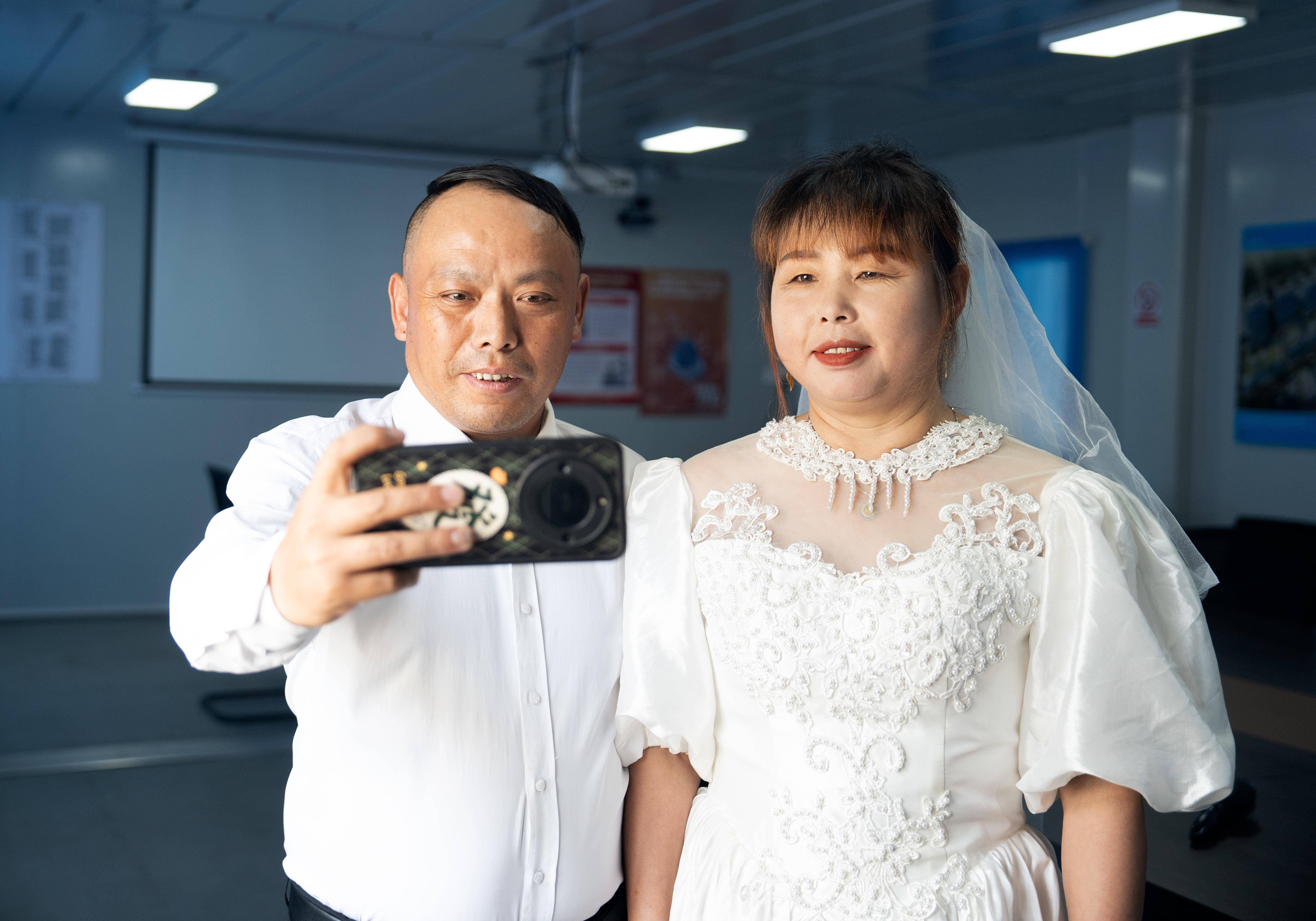 新华社发(程志兵摄)8月9日,一对工友夫妻在建设工地合影留念.