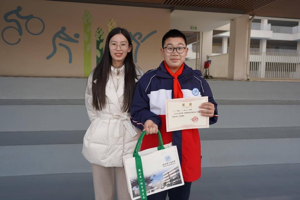 杭州市丁信中学教育处副主任胡林松叶老师为703班梅洲同学颁发"荷信