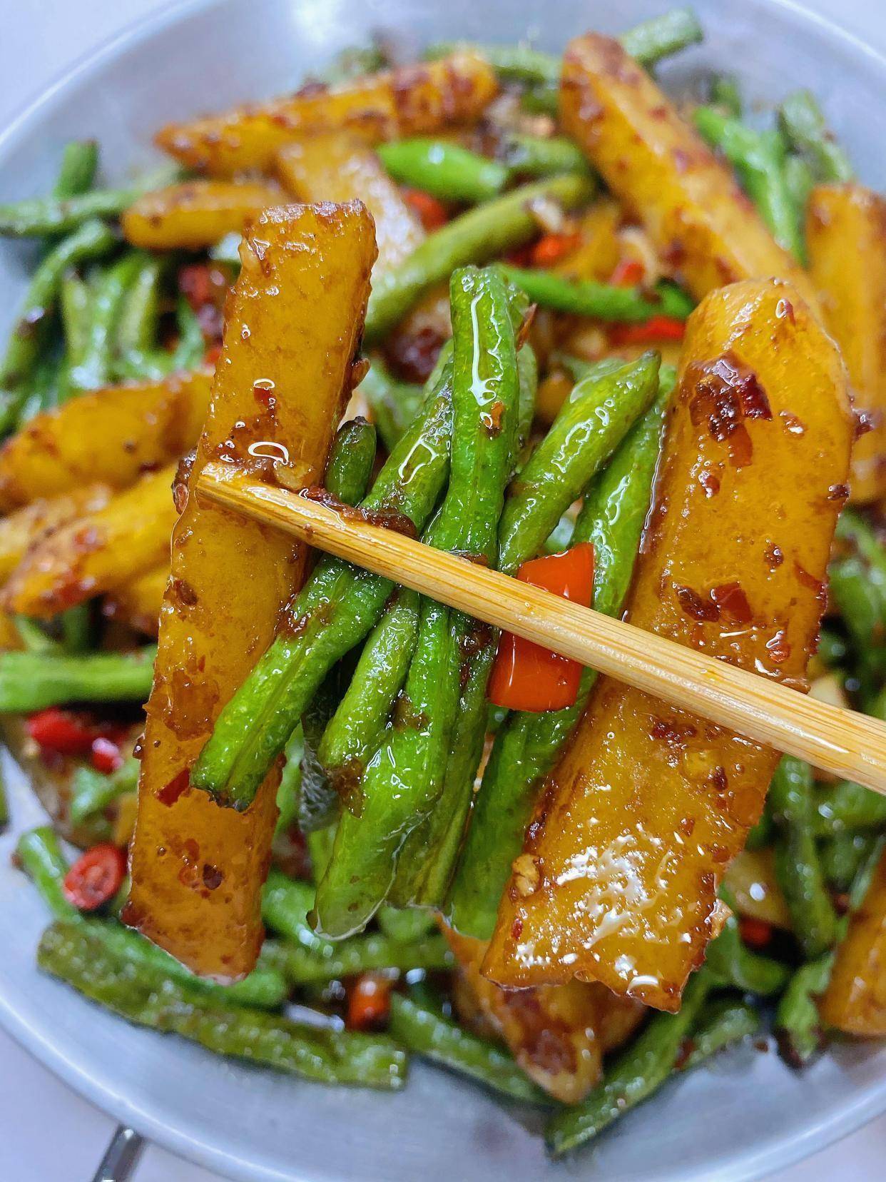 倒入四季豆翻炒至表皮起皱,加土豆块继续翻炒2分钟